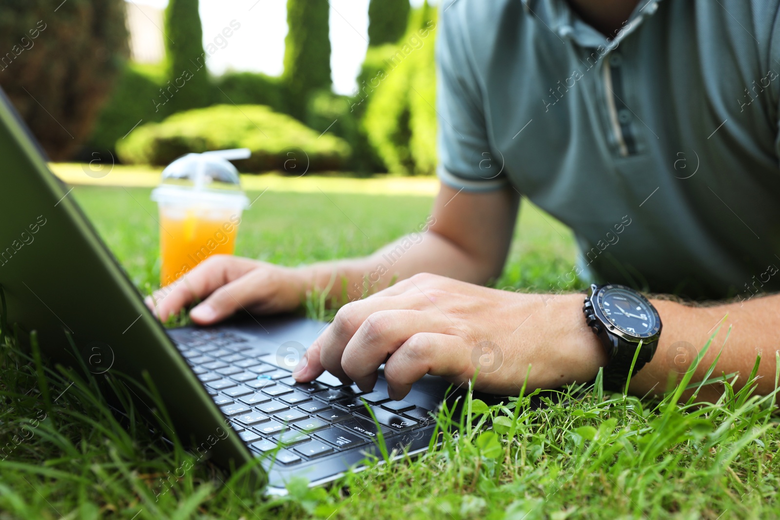 Photo of Man using laptop on green lawn outdoors, closeup