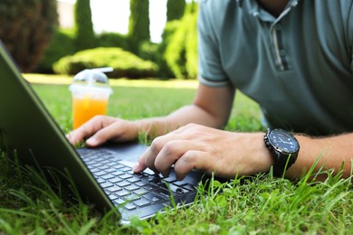 Man using laptop on green lawn outdoors, closeup