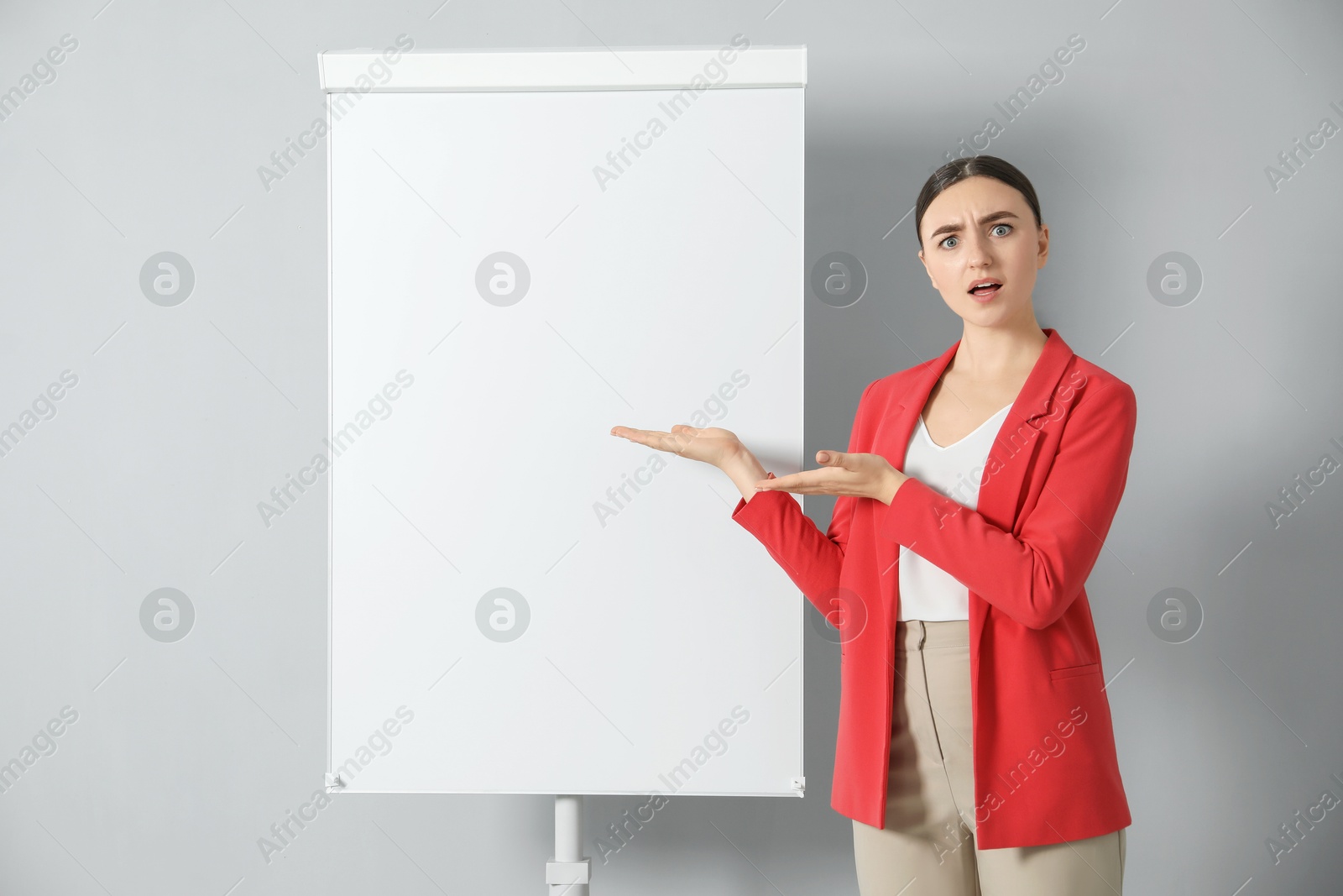 Photo of Confused woman near flip chart on grey background. Mockup for design