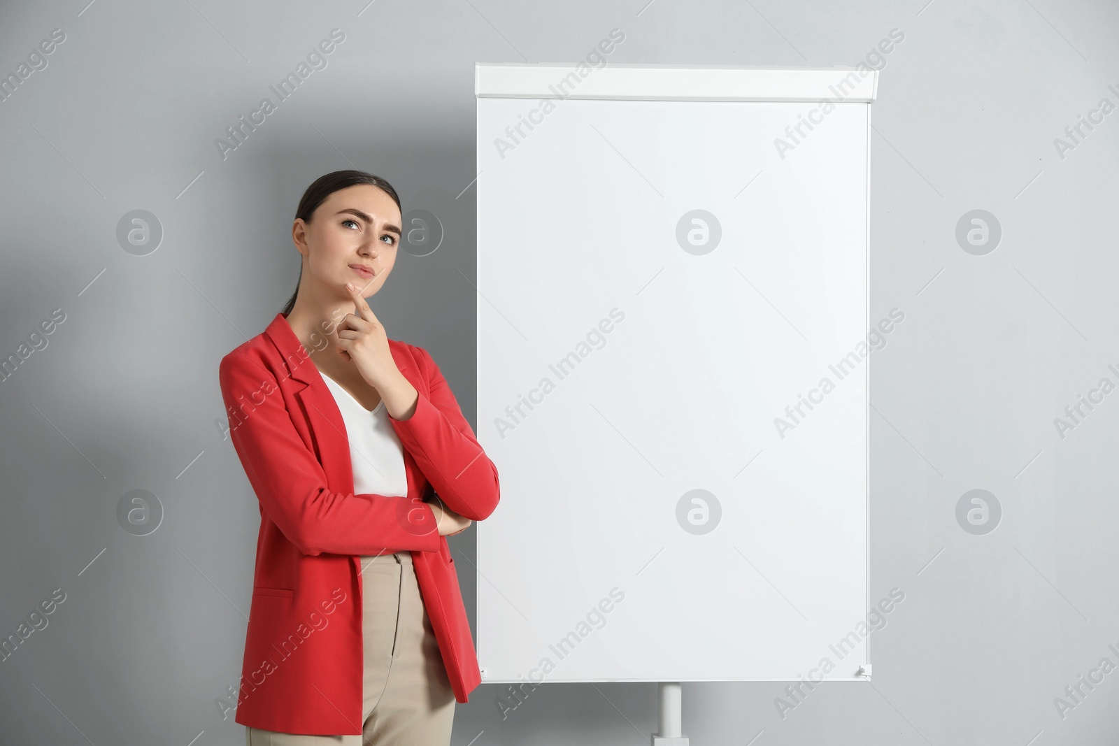 Photo of Thoughtful woman near flip chart on grey background. Mockup for design