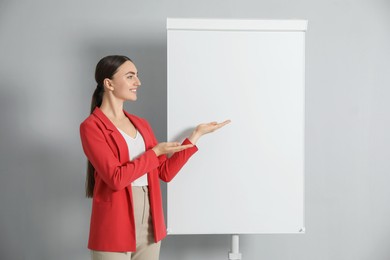 Happy woman near flip chart on grey background. Mockup for design