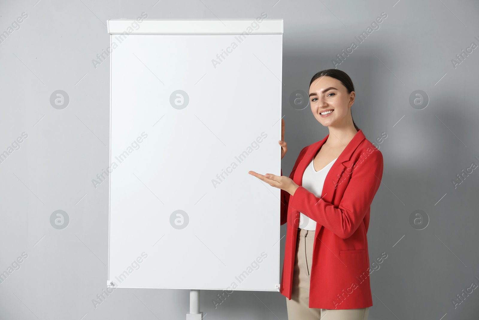 Photo of Happy woman near flip chart on grey background. Mockup for design