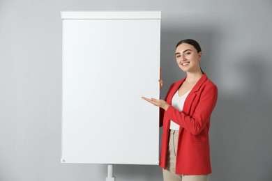 Happy woman near flip chart on grey background. Mockup for design