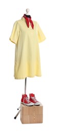 Female mannequin with stylish yellow dress, handkerchief and red sneakers isolated on white