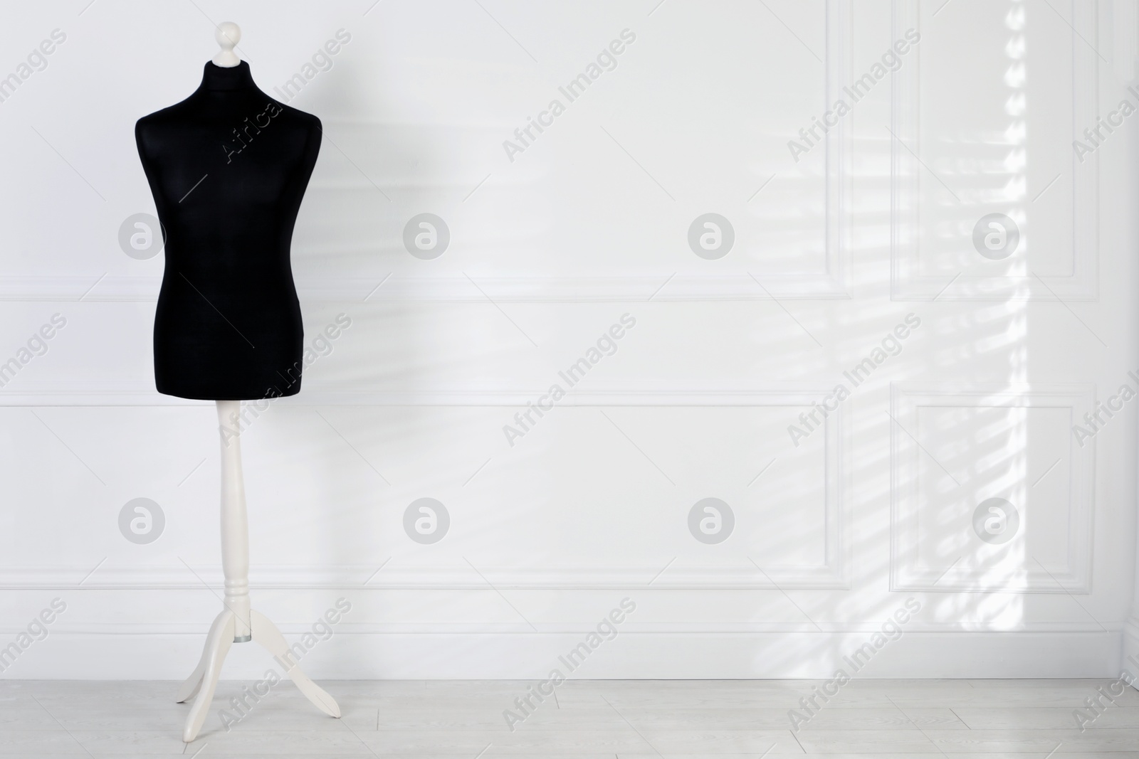 Photo of One black female mannequin near light wall. Space for text