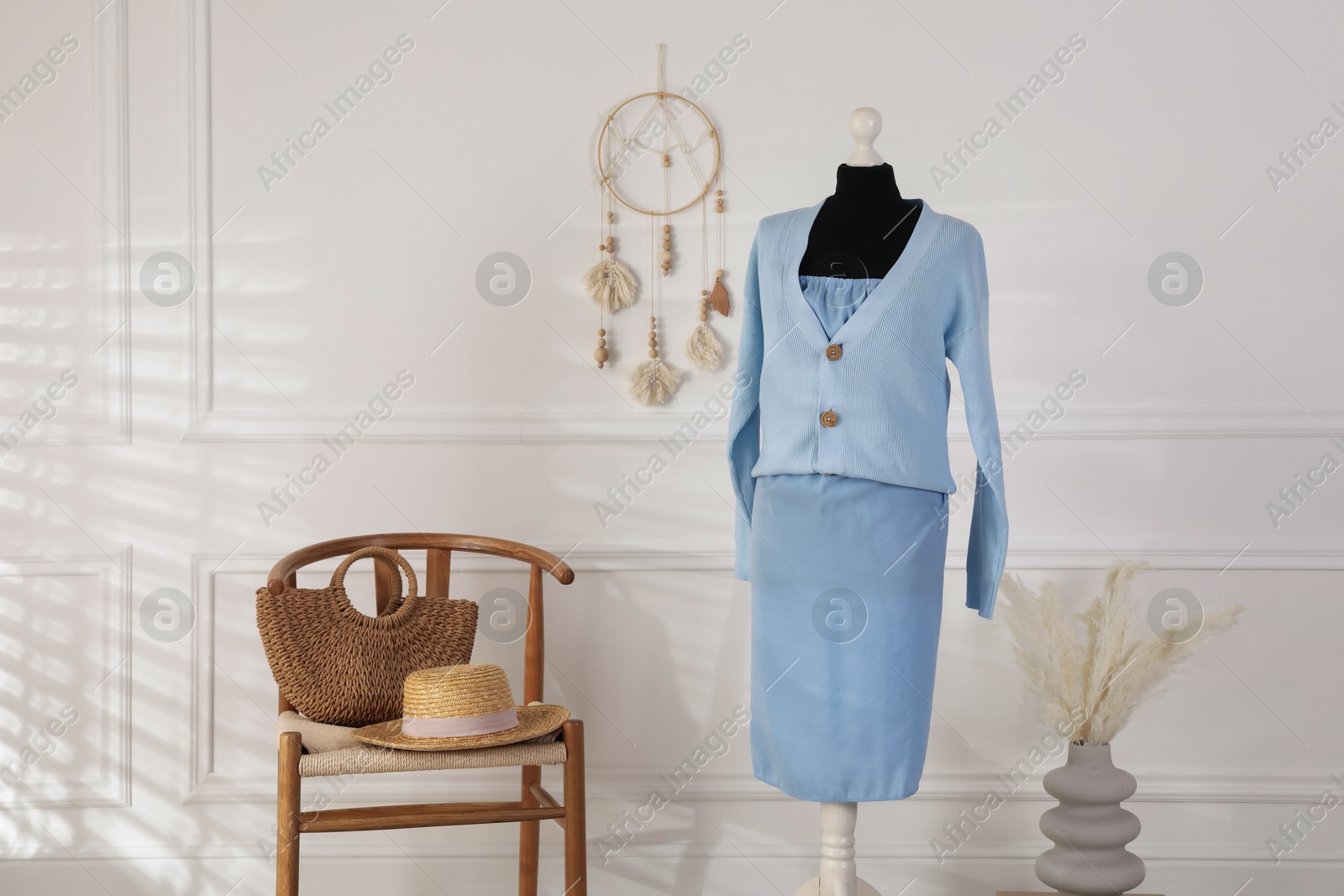 Photo of Female mannequin with clothes, chair and vase near light wall