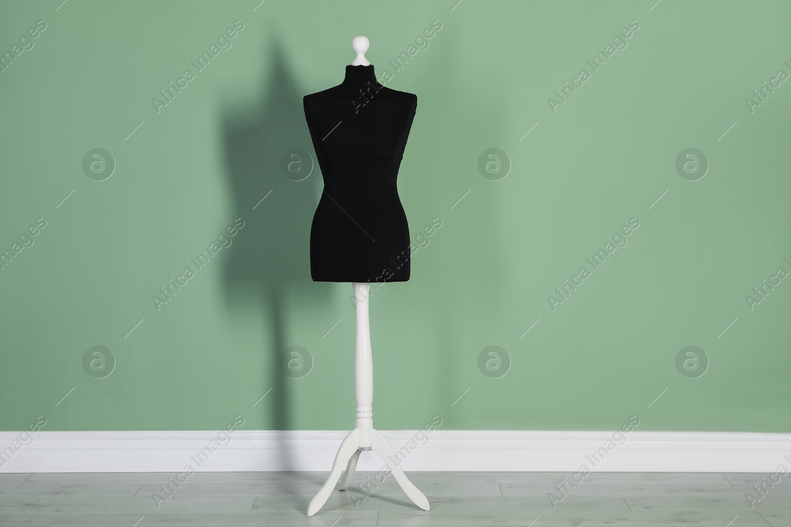 Photo of One black female mannequin near green wall