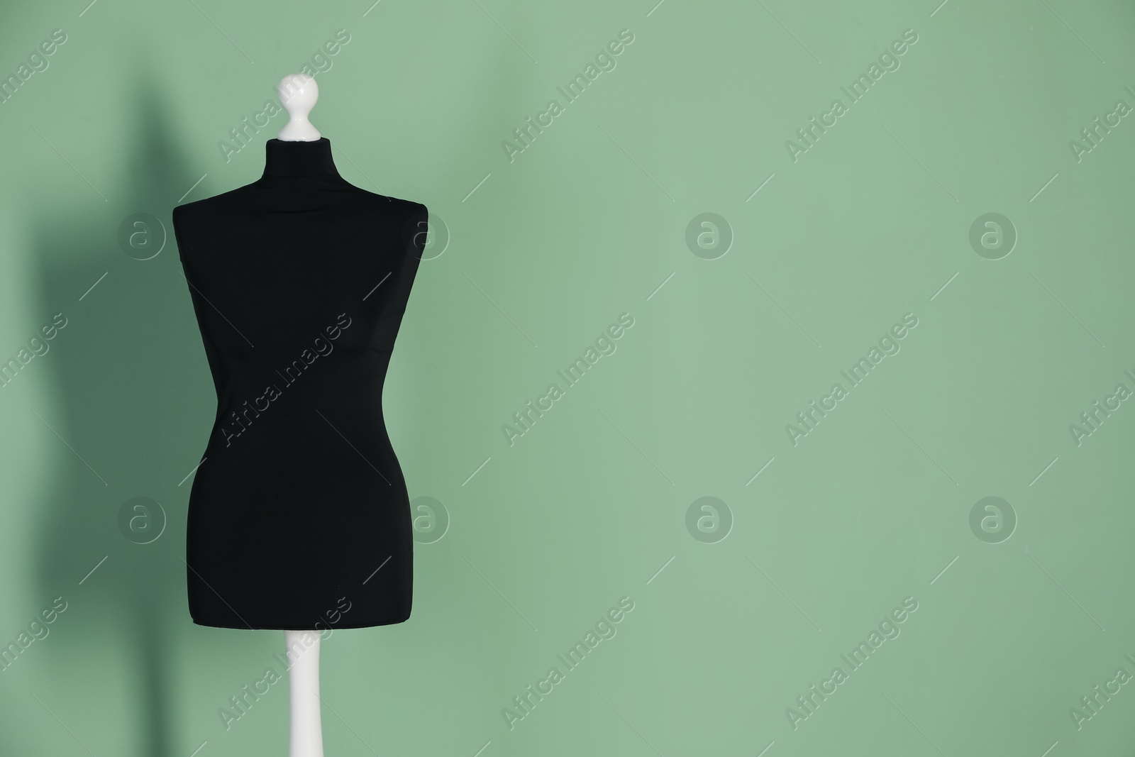 Photo of One black female mannequin near green wall. Space for text