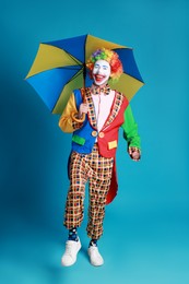 Clown with colorful umbrella on blue background