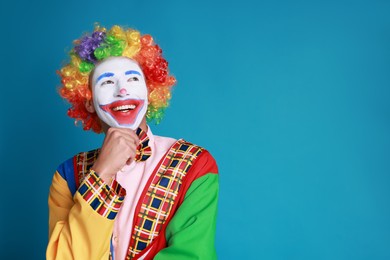 Photo of Portrait of happy clown on blue background, space for text