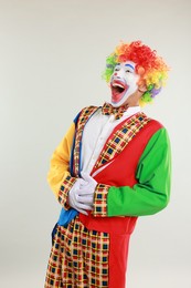 Portrait of clown laughing on light background