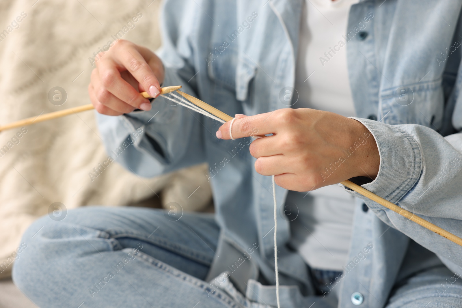 Photo of Woman knitting with needles on sofa at home, closeup