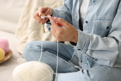 Woman knitting on sofa at home, closeup