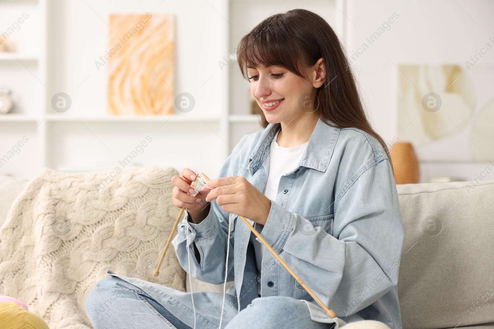 Photo of Beautiful woman knitting on sofa at home