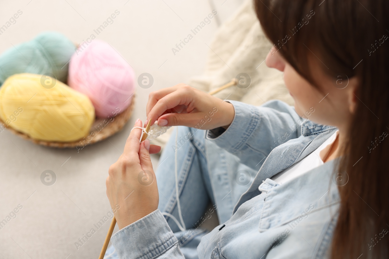 Photo of Woman knitting on sofa at home, selective focus