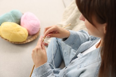 Woman knitting on sofa at home, selective focus