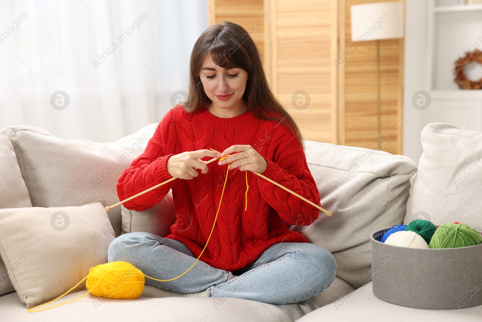 Photo of Beautiful woman knitting on sofa at home