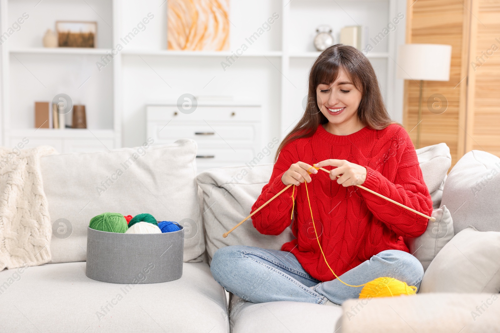 Photo of Beautiful woman knitting on sofa at home