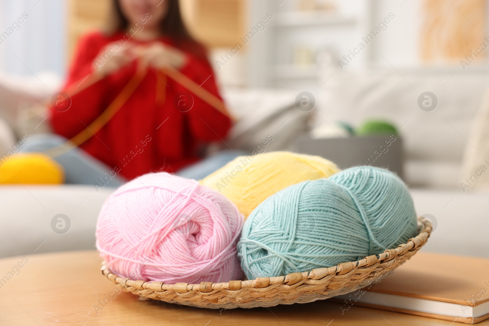 Photo of Woman knitting with needles at home, focus on colorful yarns