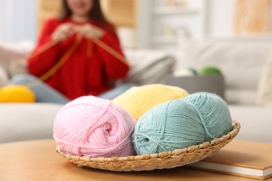 Woman knitting with needles at home, focus on colorful yarns