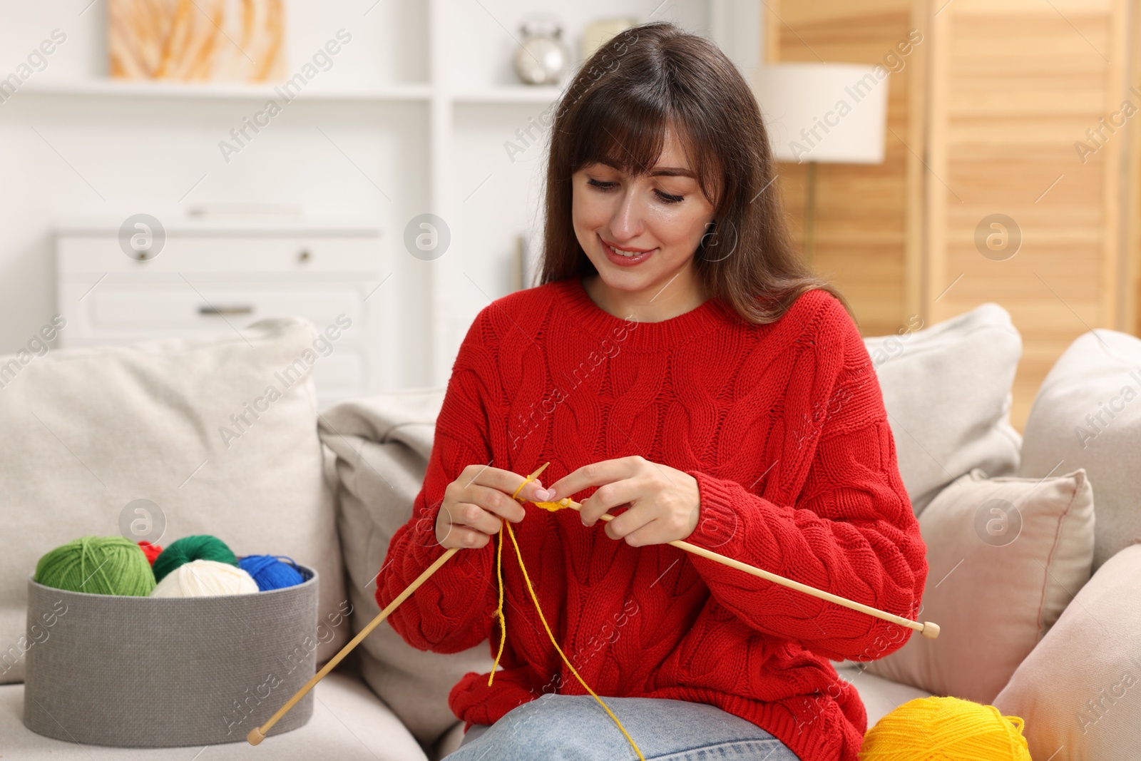 Photo of Beautiful woman knitting on sofa at home