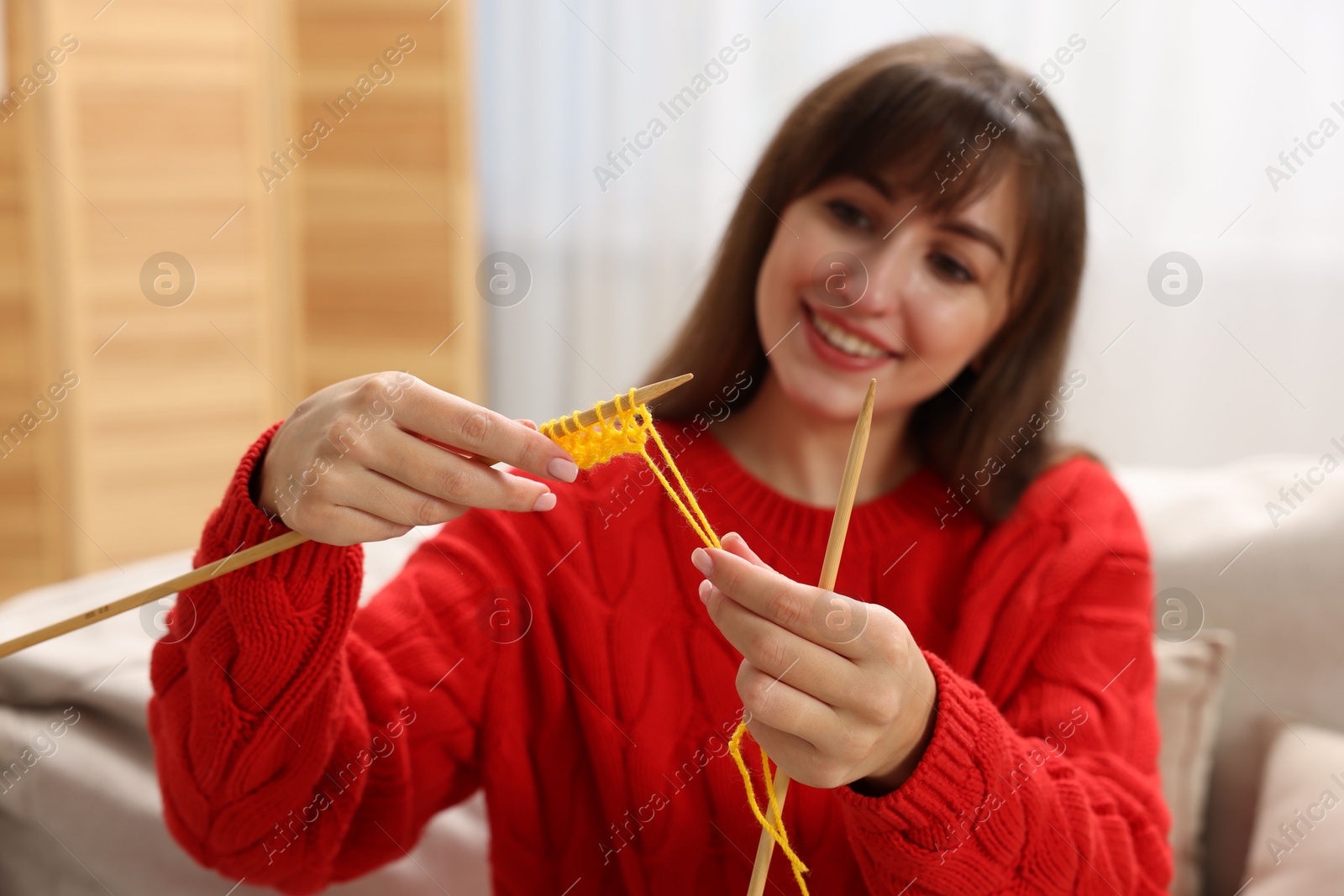 Photo of Beautiful woman knitting at home, selective focus