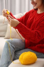 Photo of Woman knitting on sofa at home, closeup