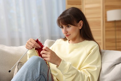 Photo of Beautiful woman knitting on sofa at home