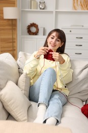 Beautiful woman knitting on sofa at home