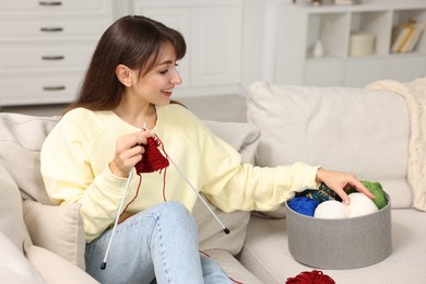 Photo of Beautiful woman knitting on sofa at home