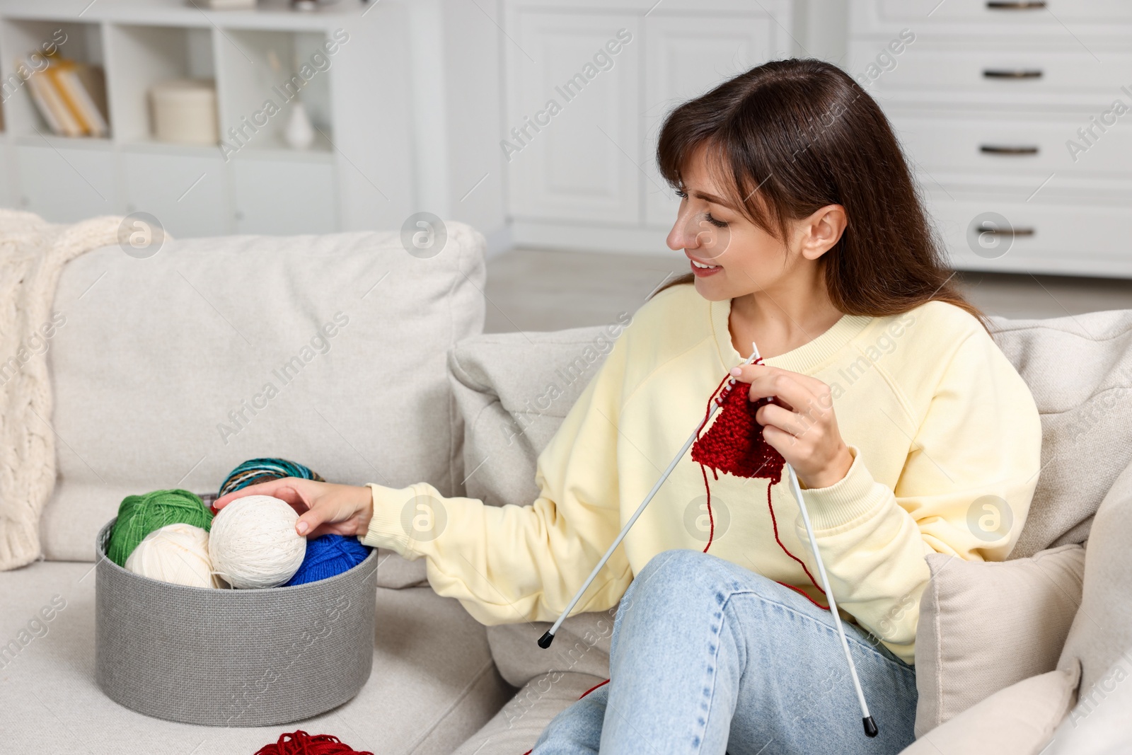 Photo of Beautiful woman knitting on sofa at home