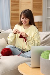 Beautiful woman learning to knit with online course at home