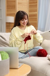 Beautiful woman learning to knit with online course at home