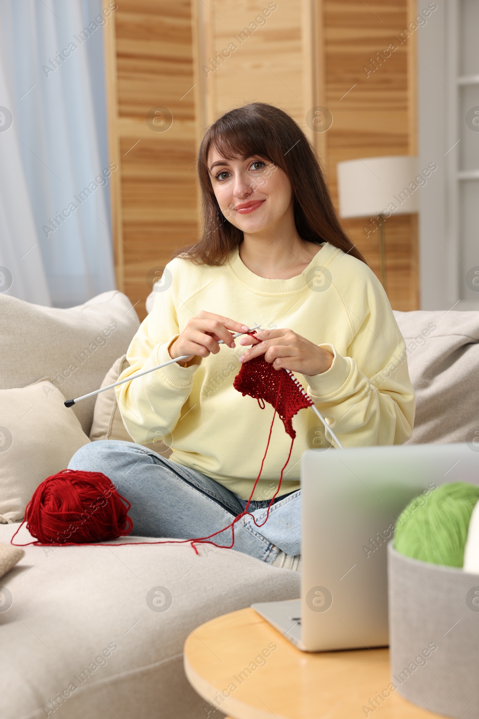 Photo of Beautiful woman learning to knit with online course at home