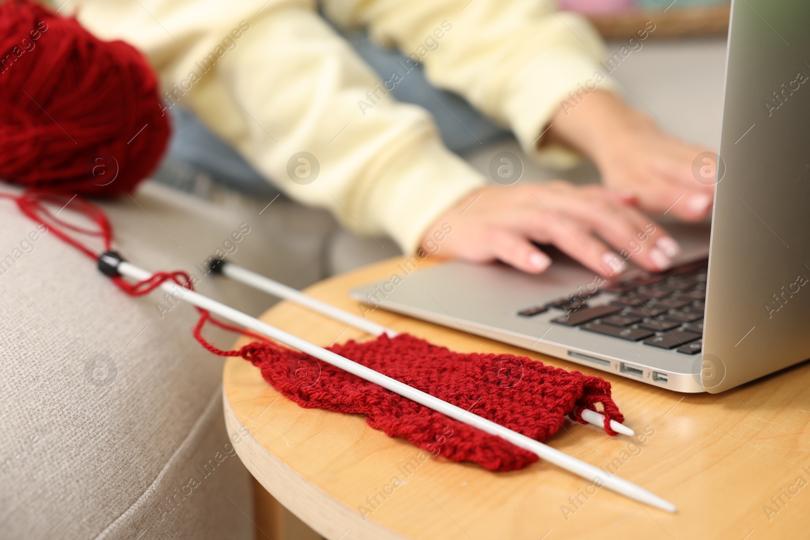 Photo of Beautiful woman learning to knit with online course at home, closeup