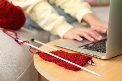 Beautiful woman learning to knit with online course at home, closeup