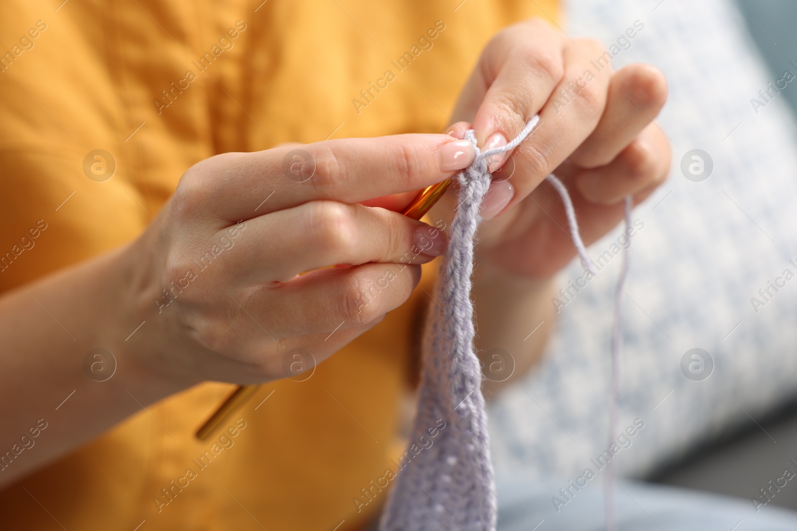 Photo of Woman crocheting with hook at home, closeup