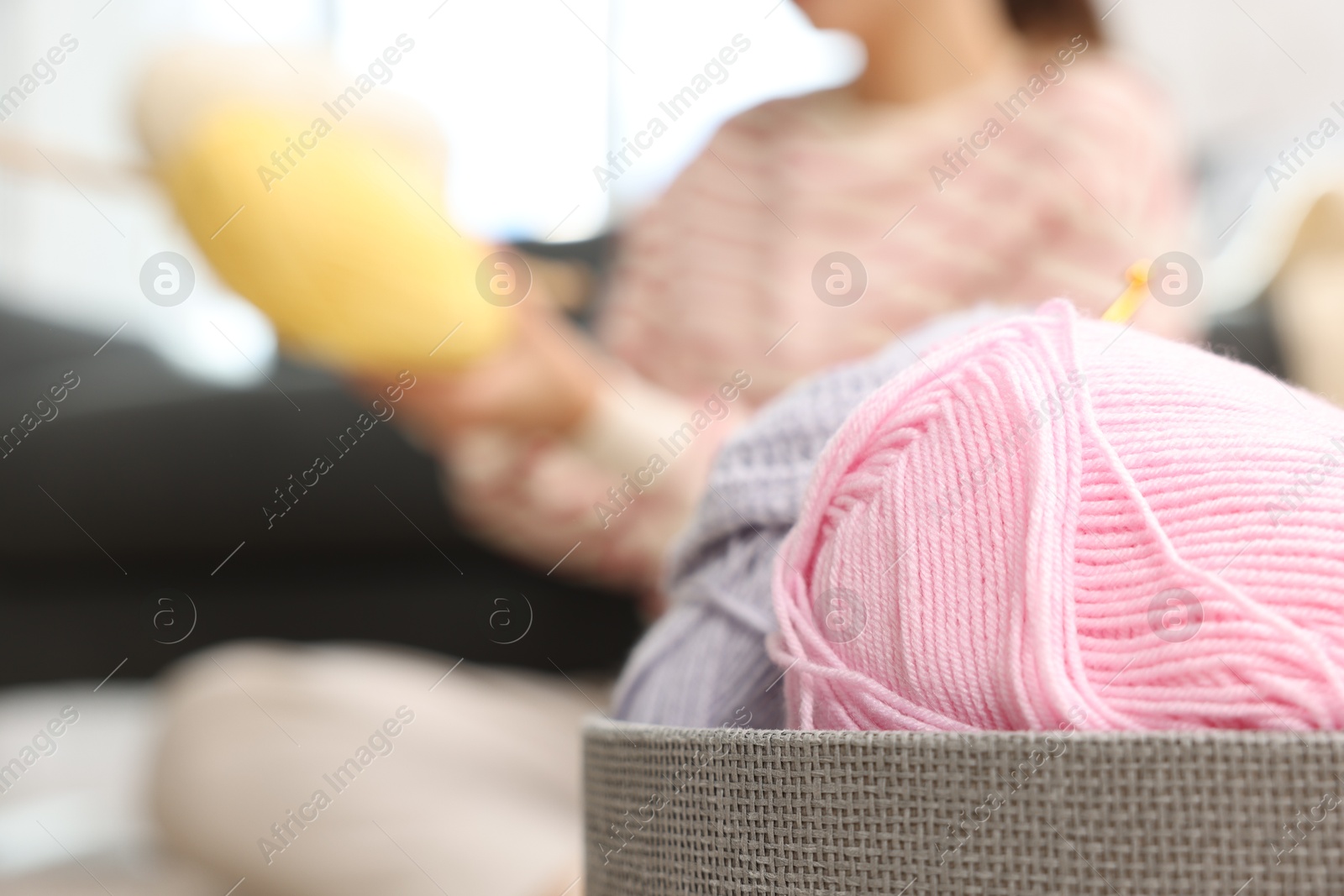 Photo of Woman knitting at home, focus on colorful yarns