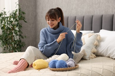 Photo of Beautiful woman with colorful yarns on bed at home. Knitting material