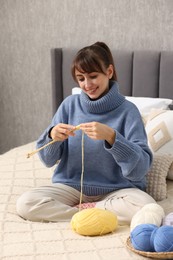 Beautiful woman knitting with needles on bed at home