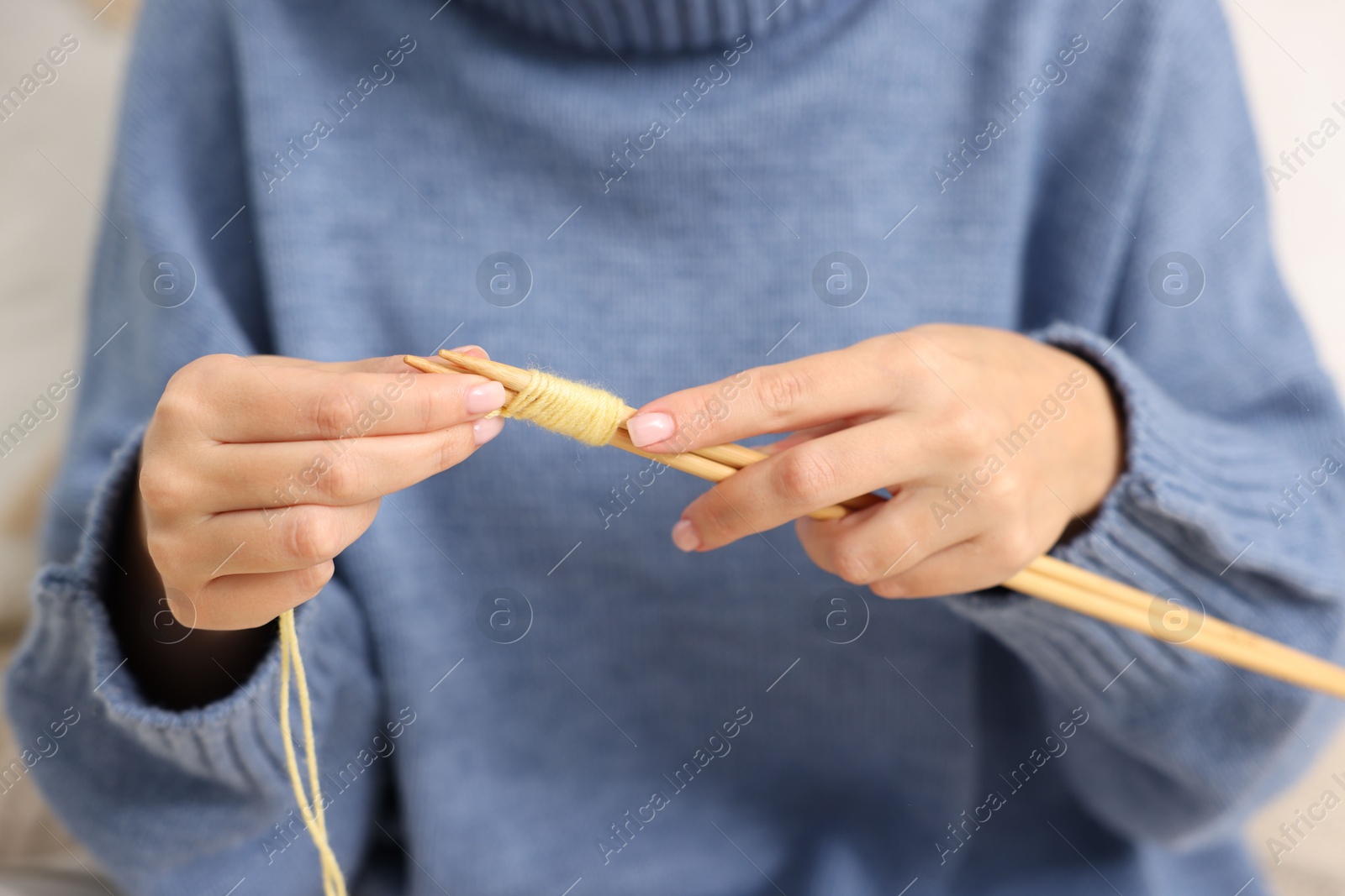 Photo of Woman knitting with needles at home, closeup