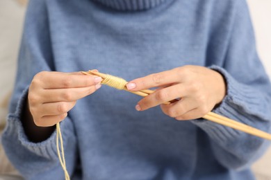 Woman knitting with needles at home, closeup