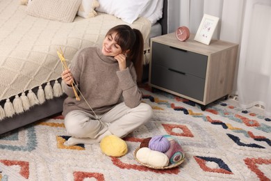 Beautiful woman knitting with needles on floor at home