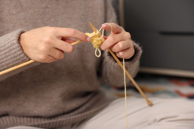 Photo of Woman knitting with needles at home, closeup