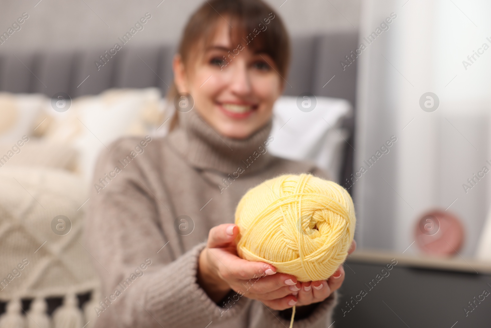 Photo of Beautiful woman with yellow yarn at home, selective focus. Knitting material