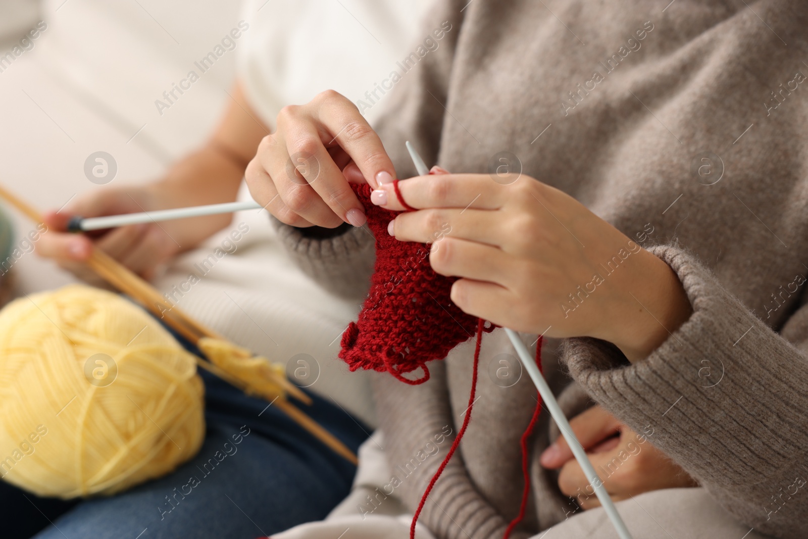 Photo of Woman teaching her boyfriend how to knit at home, closeup