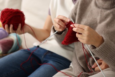 Photo of Woman teaching her boyfriend how to knit at home, closeup