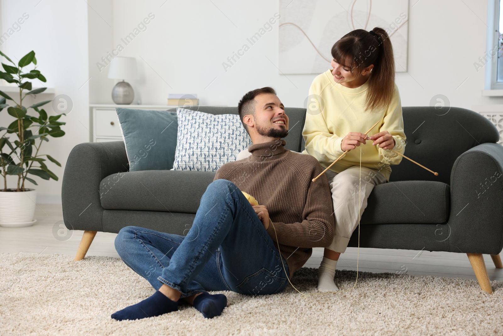 Photo of Woman teaching her boyfriend how to knit at home