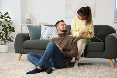 Woman teaching her boyfriend how to knit at home