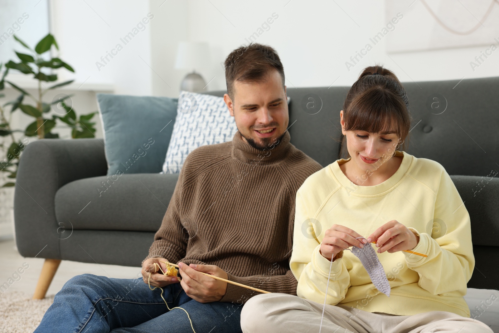 Photo of Woman teaching her boyfriend how to knit at home